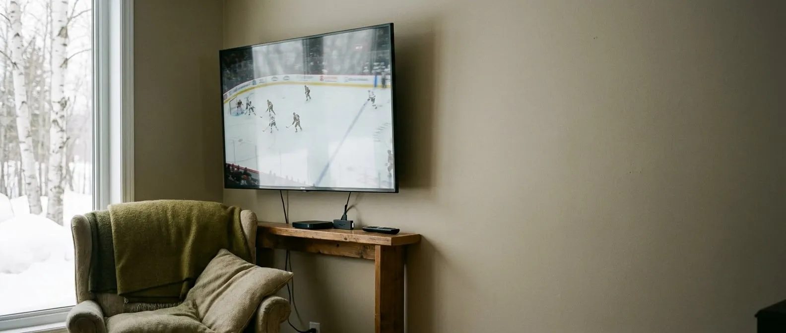 A wall-mounted television in a Canadian living room playing a live hockey broadcast on a winter afternoon.